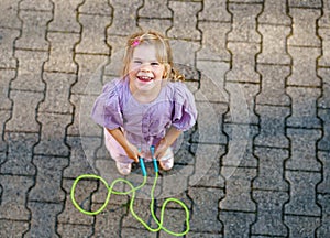 Little preschool girl jump and train with skipping rope. View from above on cute happy active child. Summer sports and