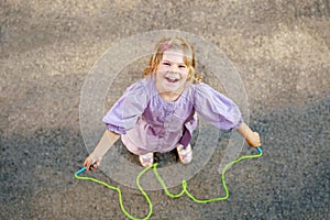 Little preschool girl jump and train with skipping rope. View from above on cute happy active child. Summer sports and