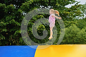 Little preschool girl jumping on trampoline. Happy funny toddler child having fun with outdoor activity in summer