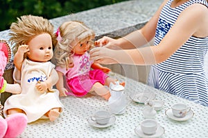 Little preschool girl playing with dolls. Happy excited child play tea party with toys. Role games for children