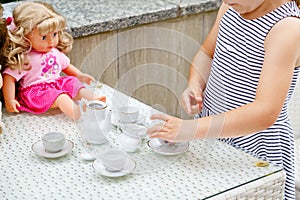 Little preschool girl playing with dolls. Happy excited child play tea party with toys. Role games for children