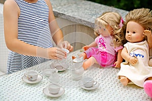 Little preschool girl playing with dolls. Happy excited child play tea party with toys. Role games for children