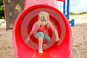 Little preschool girl playing on outdoor playground. Happy toddler child climbing and having fun with summer outdoors activity.