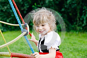 Little preschool girl playing on outdoor playground. Happy toddler child climbing and having fun with summer outdoors activity