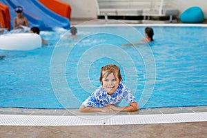 Little preschool girl playing in outdoor swimming pool in hotel resort. Child learning to swim in outdoor pool