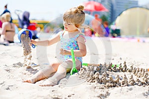 Little preschool girl playing with sand toys on the beach. Cute happy toddler child on family vacations on the sea