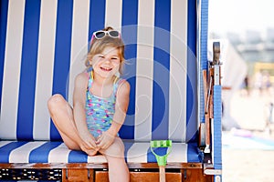 Little preschool girl resting on beach chair. Cute happy toddler child on family vacations on the sea. Kid playing