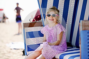 Little preschool girl resting on beach chair. Cute happy toddler child on family vacations on the sea. Kid playing