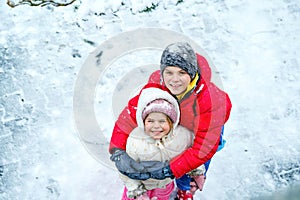 Little preschool girl and school boy playing with snow in winter. Brother and sister protraitt. Happy smiling children