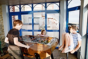 Little preschool girl and two kids school boys playing table soccer. Happy excited positive children having fun with