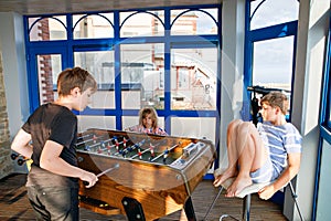 Little preschool girl and two kids school boys playing table soccer. Happy excited positive children having fun with