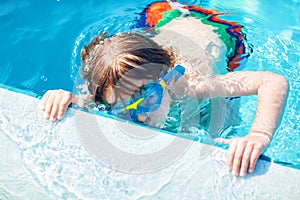 Little preschool kid boy making swim competition sport. Kid with swimming goggles reaching edge of the pool . Child