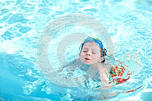 Little preschool kid boy making swim competition sport. Kid with swimming goggles reaching edge of the pool . Child