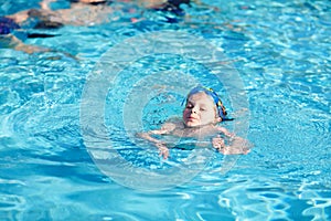 Little preschool kid boy making swim competition sport. Kid with swimming goggles reaching edge of the pool . Child