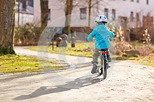 Little preschool kid boy riding with his first green bike