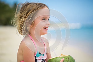 Little preschool kid girl drinking coconut juice on ocean beach.