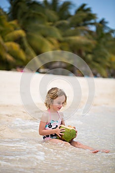 Little preschool kid girl drinking coconut juice on ocean beach.