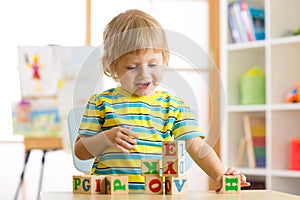 Little preschooler child boy playing with toy cubes and memorizing letters. Early education concept