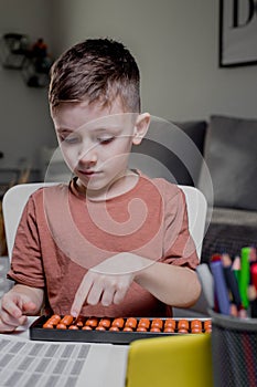 Little preschooler counting large numbers on his fingers using mental arithmetic, concept of the development of the two