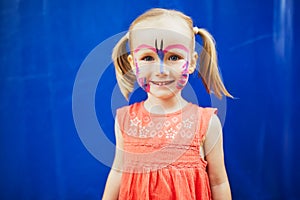 Little preschooler girl with butterfly face painting outdoors