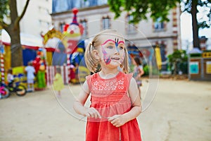 Little preschooler girl with butterfly face painting outdoors