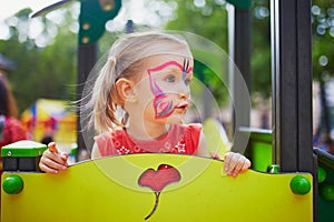 Little preschooler girl with butterfly face painting outdoors