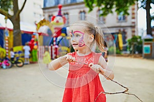 Little preschooler girl with butterfly face painting outdoors