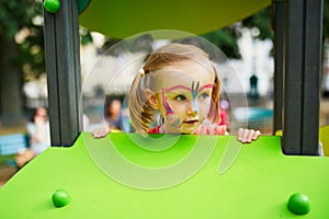 Little preschooler girl with butterfly face painting outdoors