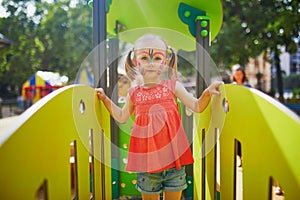 Little preschooler girl with butterfly face painting outdoors