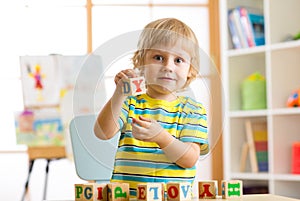 Little preschooler kid boy playing with toy cubes and memorizing letters. Early education and preschool concept