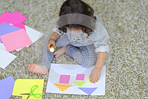 Little preschooler toddler girl gluing colorful paper.
