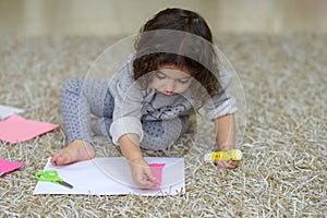 Little preschooler toddler girl gluing colorful paper.