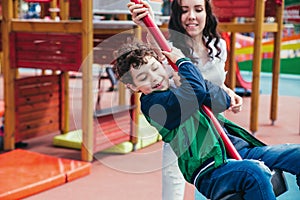 Little pretty boy is having fun outdoor. Playing in children zone in amusement park.