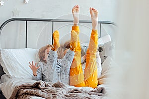 Little pretty brother and sister in pajamas lying in bed, cozy morning, focus on legs