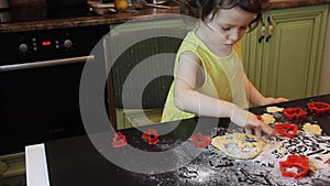 Little pretty child girl making Cinnamon Gingerbread Cookies. Christmas and New Year 2019 concept. red plastic forms, yellow dress