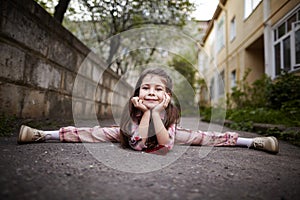 Little pretty girl doing splits outdoors