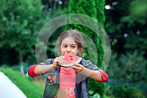 Little pretty girl eating a juicy watermelon in the garden. Children eat fruit outdoors. Healthy food for children