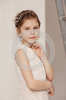 Little pretty girl with flowers dressed in wedding dresses