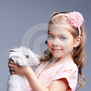 Little pretty girl holding fur rabbit baby. White cute pet at studio