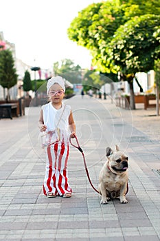 little pretty girl stylishly walking her French bulldog dog