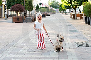 little pretty girl stylishly walking her French bulldog dog