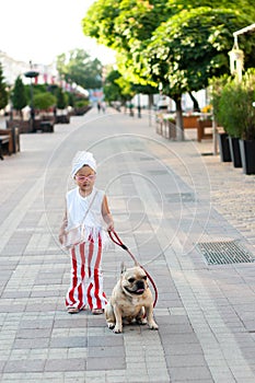 little pretty girl stylishly walking her French bulldog dog