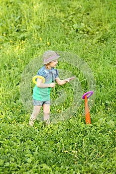 Little pretty girl throws rings at green meadow at