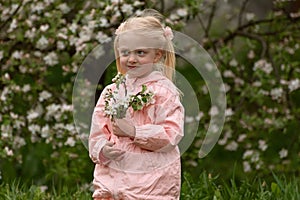 Little pretty girl with two tails enjoy spring apple blooming. Springtime. Preschool girl in flowering garden