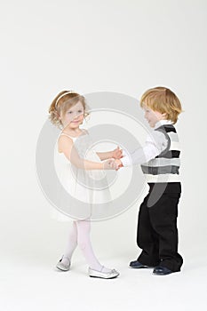 Little pretty smiling girl and boy dance on white