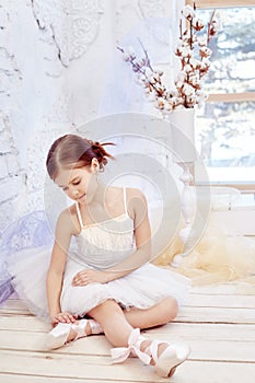 Little prima ballet. Young ballerina girl is preparing for a ballet performance. Girl in a white ball gown and Pointe