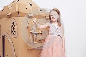 Little princess in crown play with her cardboard castle. True emotion of happiness of the child.