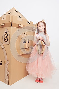 Little princess in crown play with her cardboard castle. True emotion of happiness of the child.