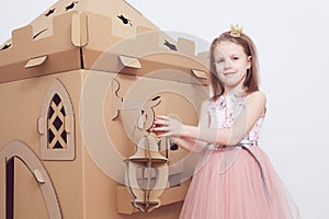 Little princess in crown play with her cardboard castle. True emotion of happiness of the child.