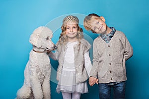 Little princess and handsome boy with Royal poodle. Love. Friendship. Family. Studio portrait over blue background